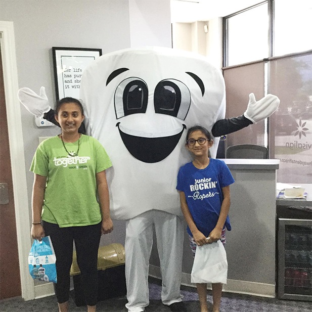 Two young people with tooth mascot