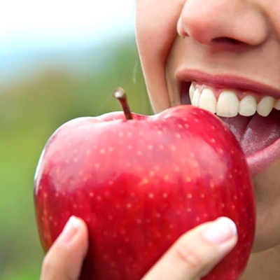 close up of person eating red apple