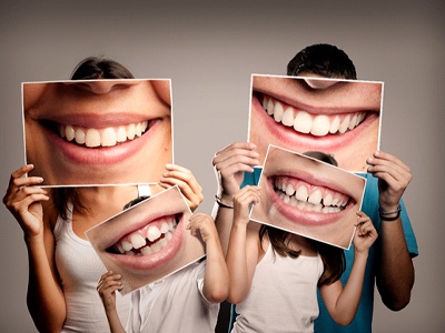 Family holding portraits of smiles at their Guardian dentist.