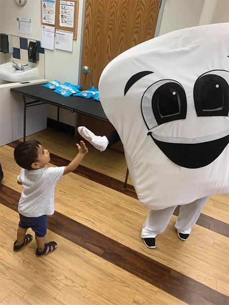Child giving tooth mascot a high five