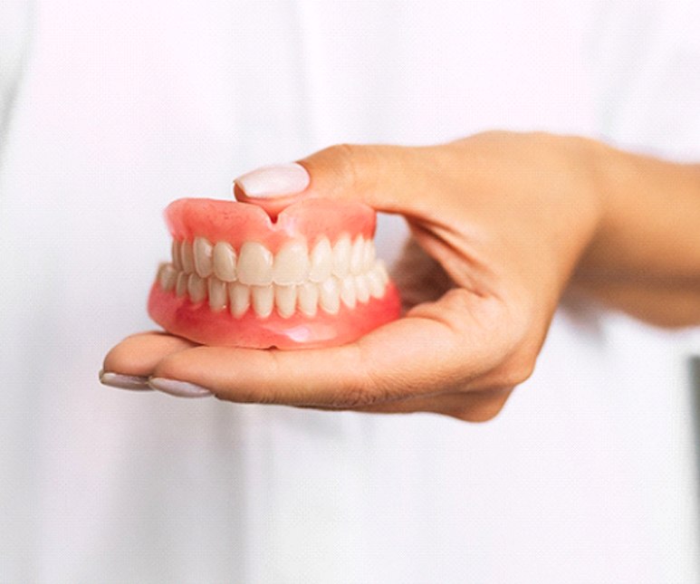Dentist holding dentures in Frisco