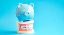 Piggy bank resting on top of a model of teeth