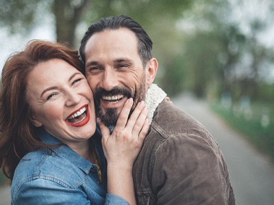 A middle-aged couple laughing and smiling after seeing their GEHA dentist in Frisco