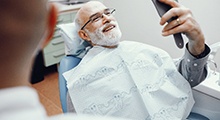 Older man smiling with an implant dentist in Frisco