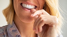 Closeup of woman placing Invisalign aligners on top teeth