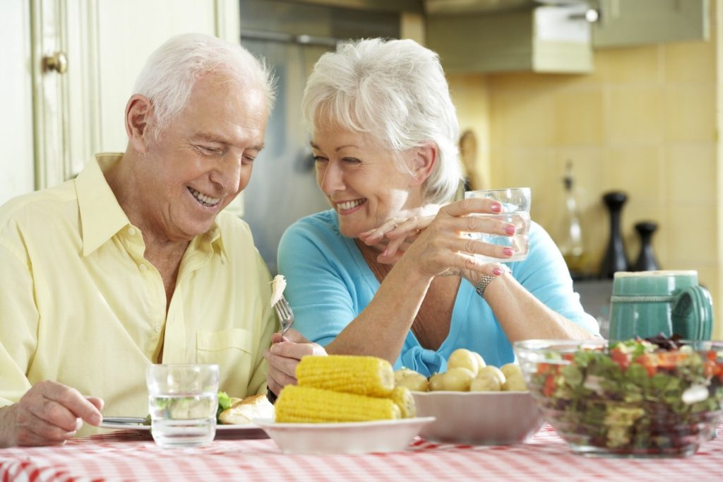 Elderly couple eating corn with dental implants