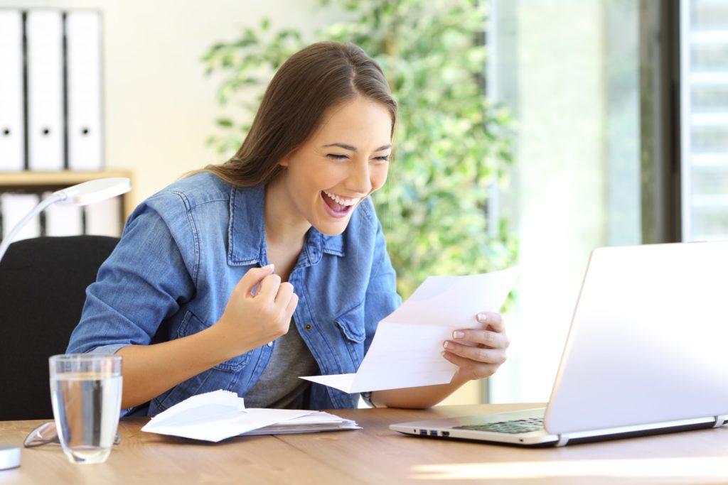 Woman smiling while reading paperwork with tax refund